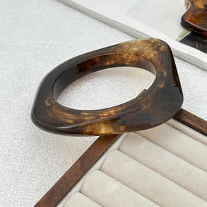 Vue détaillée d'un bracelet en résine écaille sur un plateau à bijoux blanc