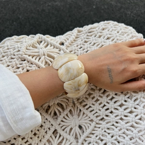 Detail view of retro irregular wavy resin cuff bracelet with cream marble pattern on a wrist