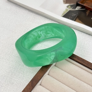 Detailed view of wide translucent green resin bangle with marble effect and smoke pattern