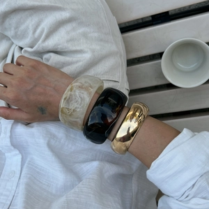 Three-piece stackable bangle set with cream marble resin, black resin, and gold metal
