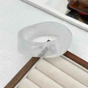 Close-up of a wide translucent acrylic bangle with marble texture and gold foil resin detail