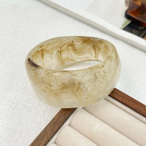 Detail of wide resin bangle with amber marble texture on a jewelry display box