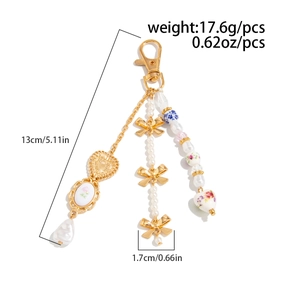 Detail of keychain with ceramic floral charms, faux pearls and a golden bow pendant