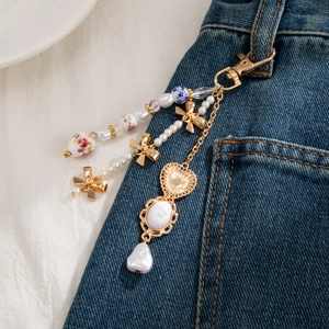Blue floral ceramic heart and bow pearl keychain hanging on denim pocket