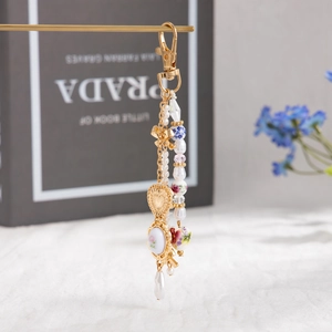 Detail of floral ceramic beads and pearl tassels on a golden heart bag charm pendant