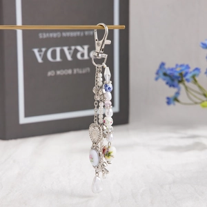 Detail of ceramic floral beads and heart charm on a pearl tassel keychain for bags