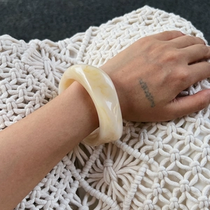 Detailed view of the marbled yellow resin wide bangle with smooth geometric textures