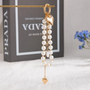 Fashionable double-row pearl keychain with gold heart pendants and a circular clasp