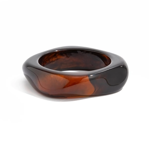 Detailed macro view of wide amber resin bangle with irregular geometric tortoiseshell pattern