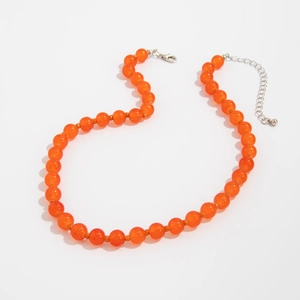 Detail van oranje doorschijnende kralenketting met metalen karabijnslot en verlenging