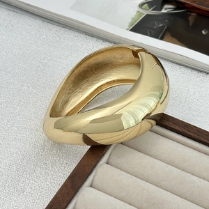 Detailed macro shot of a wide polished gold metal cuff bracelet on a jewelry display tray