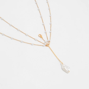 Close-up of gold layered chain body jewelry featuring pearls and a baroque pearl drop