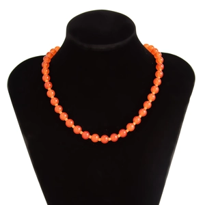 Detailoverzicht van doorschijnende oranje kralenketting op een zwarte sieradenstand