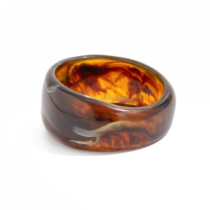 Close-up of wide resin bangle featuring amber tortoiseshell patterns and polished finish