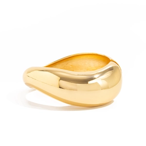 Close-up of a polished gold-plated sculpture cuff bracelet with a chunky drop design