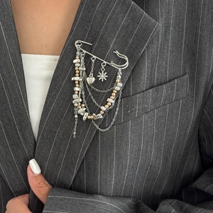 Detail of multi-layered gold and silver tassel brooch with heart and star charms on a blazer