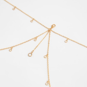Close-up of golden body chain featuring crystal pendants and secure lobster clasp