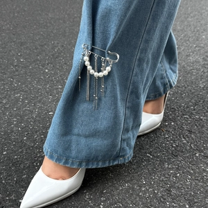 Broche en perles avec chaînes à franges argentées fixée sur un jean pour un look stylé