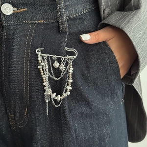 Detail of multi-layer tassel chain brooch with heart and star charms on denim jeans