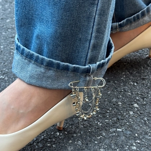 Detail view of multi-layer hip-hop chain with star charms pinned to denim jeans