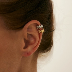 Detailopname van getextureerde gouden en zilveren clip-on oorbellen met gehamerde golven
