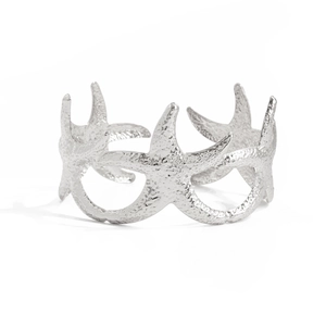 Detailopname van zilveren zeester armring met gehamerde metallic textuur en design