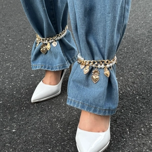 Boho layered gold chain anklet with imitation pearls and heart charms on denim jeans
