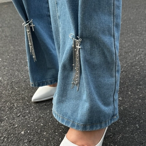 Catena con croce e nappa su jeans con dettaglio spilla da balia in stile street