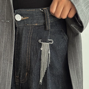 Detail of silver star tassel pin brooch showing metallic fringe on denim fabric