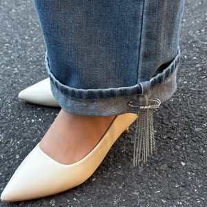 Spilla a stella in argento con strass e nappa su jeans blu e décolleté bianche