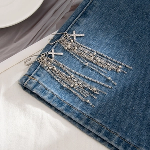 Spilla a croce d'argento con strass e lunghe nappe a catena su tessuto denim