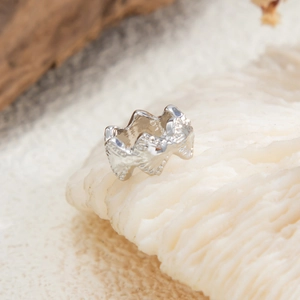 Macro-opname van zilveren ring met lavatextuur op wit koraal, minimalistisch design