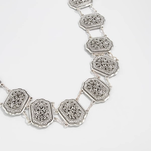 Detail of silver embossed rectangle links with vintage floral patterns and hollow design