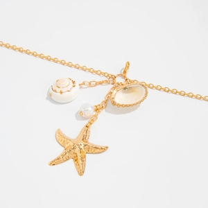 Detailed close-up of golden starfish, sea shells and pearl charms on a delicate chain