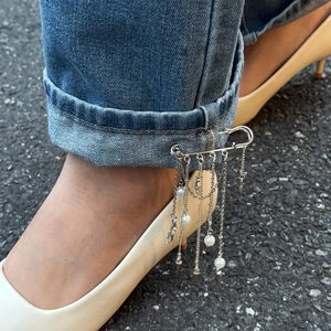 Detail of silver star tassel brooch pin with pearls styled on blue denim jeans