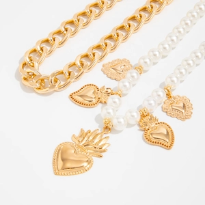 Dettaglio catena dorata e perle con ciondoli a forma di cuore sacro in stile vintage
