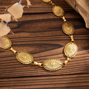 Detailed macro view of vintage gold engraved oval medallions on a bohemian body chain