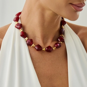 Detail of dark red resin bead necklace with golden square accents on female model