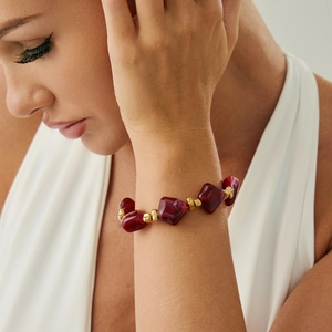 Close-up of deep wine red irregular resin beads and gold spacer beads on a bracelet