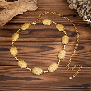 Close-up of bohemian gold waist chain with oval sunburst engraved metal plates
