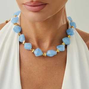 Macro detail of irregular light blue resin beads and gold spacer beads on a choker