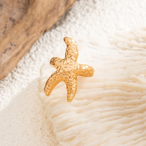 Macro-opname van een gouden zeester ring met korrelige textuur op wit koraal