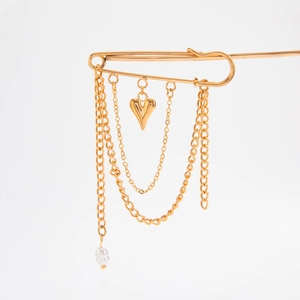 Macro detail of golden multilayer heart pendant brooch with faux pearl and chains