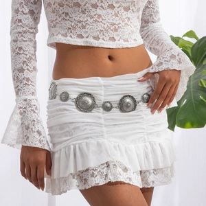 Detail of bohemian silver disc waist chain on a white ruffled lace mini skirt