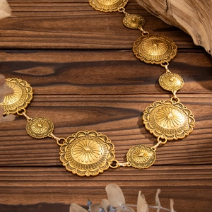 Detail of vintage gold waist chain with textured medallions on rustic wood background
