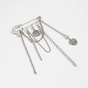 Detail of silver heart and coin charms hanging from a vintage style safety pin brooch