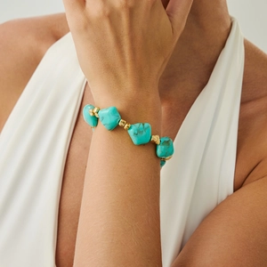 Detailed shot of turquoise beaded bracelet with gold accents worn on woman wrist