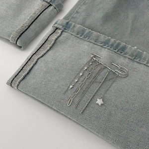 Silver safety pin brooch with star fringe chains on denim fabric for punk style
