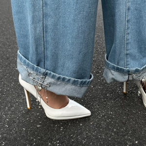 White pointed high heels with denim jeans featuring silver heart pendant tassel chains