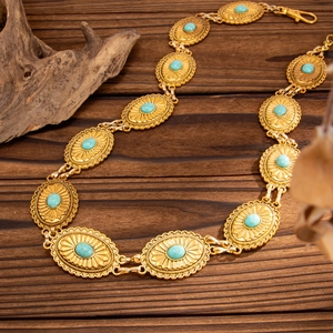 Macro detail of Bohemian gold metal waist chain with turquoise resin oval stones